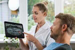 Dentist showing and explaining a dental X-ray with an impacted wisdom tooth to a patient during a consultation