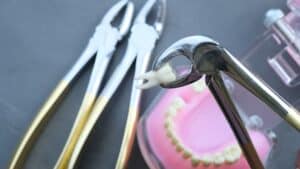 Dental instruments, including tooth forceps and an artificial teeth model, used for tooth extraction and dental studies.
